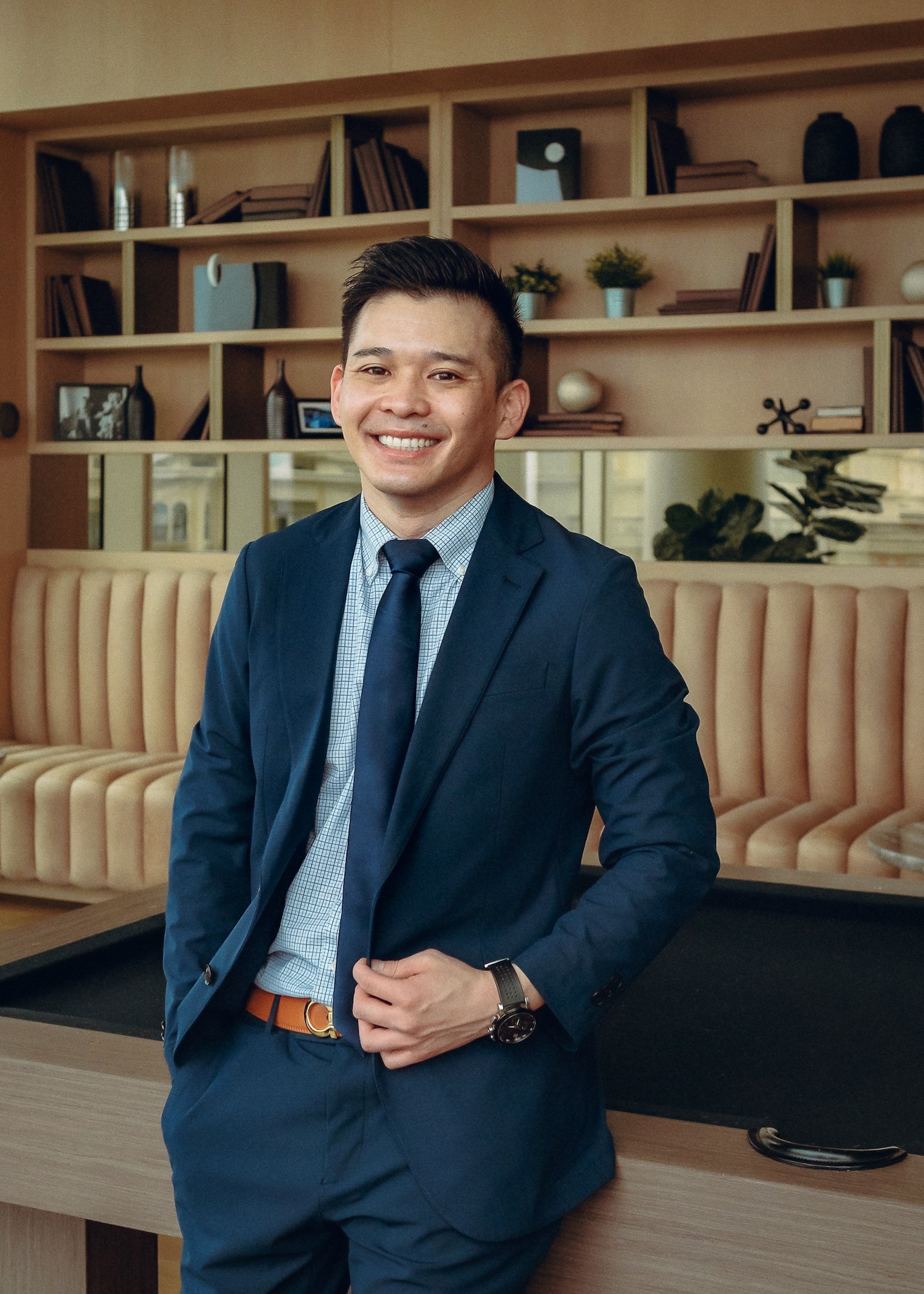 Attorney Ron Ruangtragool standing in front a pool table with his hand holding his blazer and a smile on his trustworthy face.